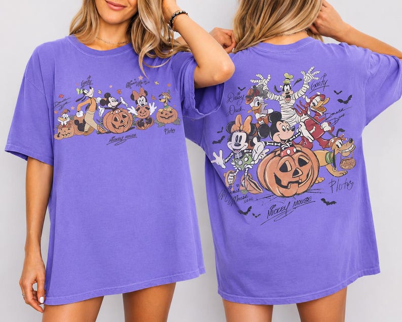 May include: Purple t-shirt featuring a Halloween-themed graphic with Mickey Mouse, Minnie Mouse, Goofy, Donald Duck, and Pluto characters. The front and back of the shirt display the characters with pumpkins and bats.