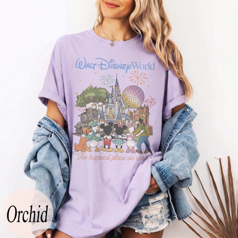 Puede incluir: Camiseta lila claro con un dise&ntilde;o de Walt Disney World, con Mickey Mouse y sus amigos. El texto dice "Walt Disney World" y "The happiest place on earth".