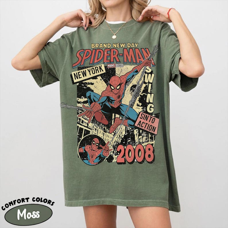 May include: Moss green t-shirt with a vintage Spider-Man graphic. The design includes the words "BRAND NEW DAY", "SPIDER-MAN", "NEW YORK", and "2008". The shirt is made of Comfort Colors material.