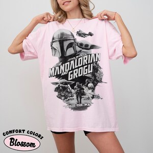 Op de afbeelding: Lichtroze t-shirt met een zwart-wit afbeelding van personages uit de Star Wars-serie, "The Mandalorian and Grogu". Het shirt heeft ook de tekst "This is the Way".