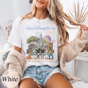 Puede incluir: Camiseta blanca con un gr&aacute;fico colorido de Walt Disney World con Mickey Mouse, Minnie Mouse y otros personajes. El texto "Walt Disney World" y "The happiest place on earth" est&aacute;n impresos en la camiseta.