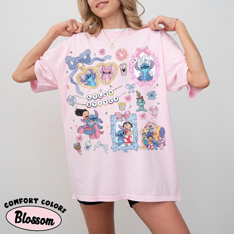 May include: A light pink t-shirt featuring cartoon illustrations of Stitch and other characters. The shirt has the words "Lilo & Stitch" and "Comfort Colors Blossom" printed on it. The design includes frames, bows, and various decorative elements.