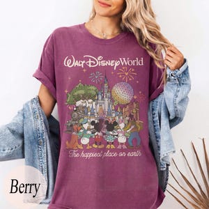 Puede incluir: Camiseta color bayas con un gr&aacute;fico de Walt Disney World con Mickey y Minnie Mouse, el Pato Donald y Goofy. El texto "Walt Disney World" y "The happiest place on earth" est&aacute;n impresos en la camiseta.