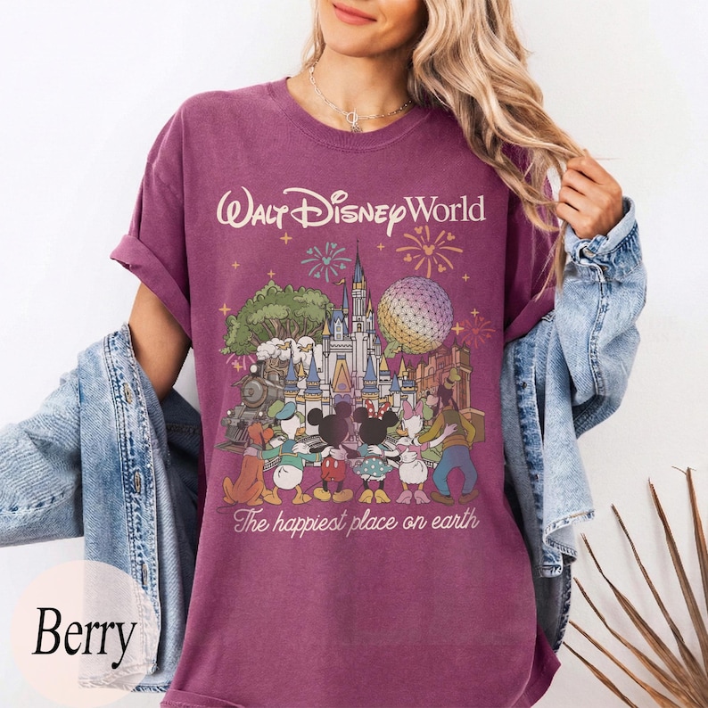 Puede incluir: Camiseta color bayas con un gr&aacute;fico de Walt Disney World con Mickey y Minnie Mouse, el Pato Donald y Goofy. El texto "Walt Disney World" y "The happiest place on earth" est&aacute;n impresos en la camiseta.