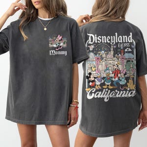 May include: Dark gray t-shirt featuring a Minnie Mouse graphic with the word "Mommy" on the front. The back of the shirt displays a Disneyland graphic with various Disney characters and the text "Disneyland Est. 1955 California."