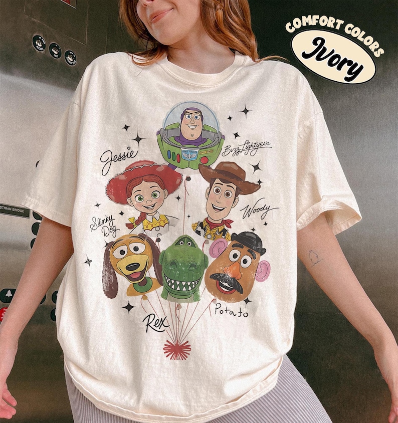 Puede incluir: Camiseta de color marfil con un gr&aacute;fico de personajes de la pel&iacute;cula de animaci&oacute;n Toy Story. El dise&ntilde;o incluye a Buzz Lightyear, Woody, Jessie, Slinky Dog, Rex y Mr. Potato Head. Las palabras "Comfort Colors" e "Ivory" tambi&eacute;n est&aacute;n impresas en la camiseta.