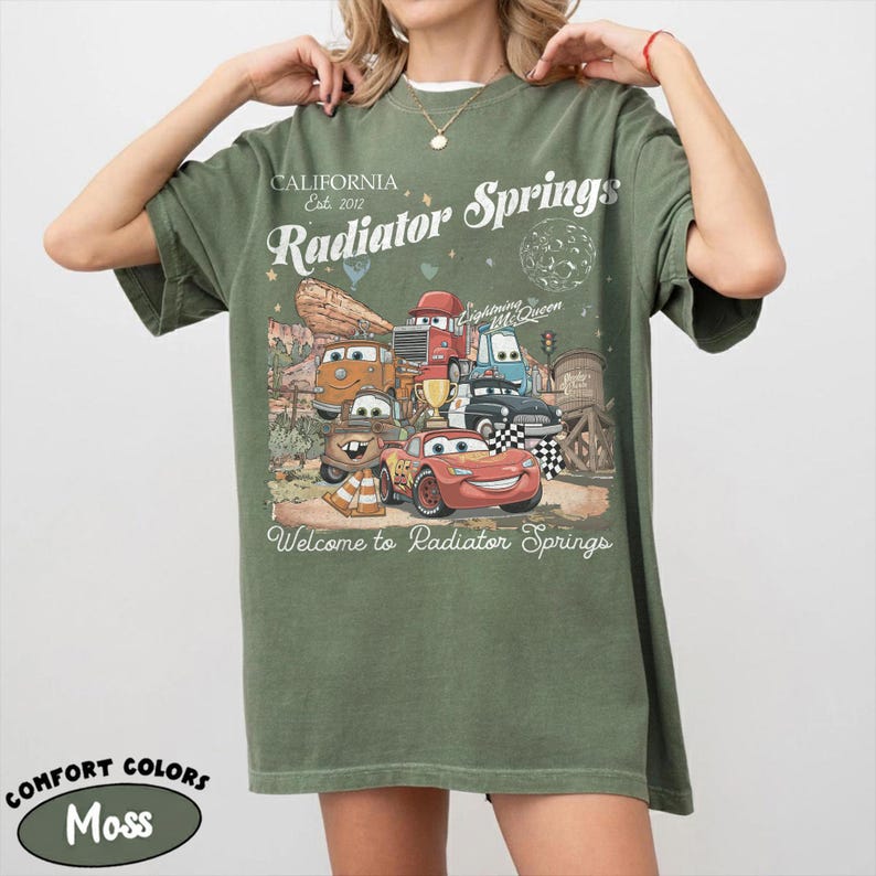 以下が含まれることがあります： モスグリーンのTシャツ。映画「カーズ」のキャラクターのグラフィックが特徴で、「California Est. 2012 Radiator Springs」と「Welcome to Radiator Springs」の文字が入っています。Comfort Colorsブランドのシャツです。