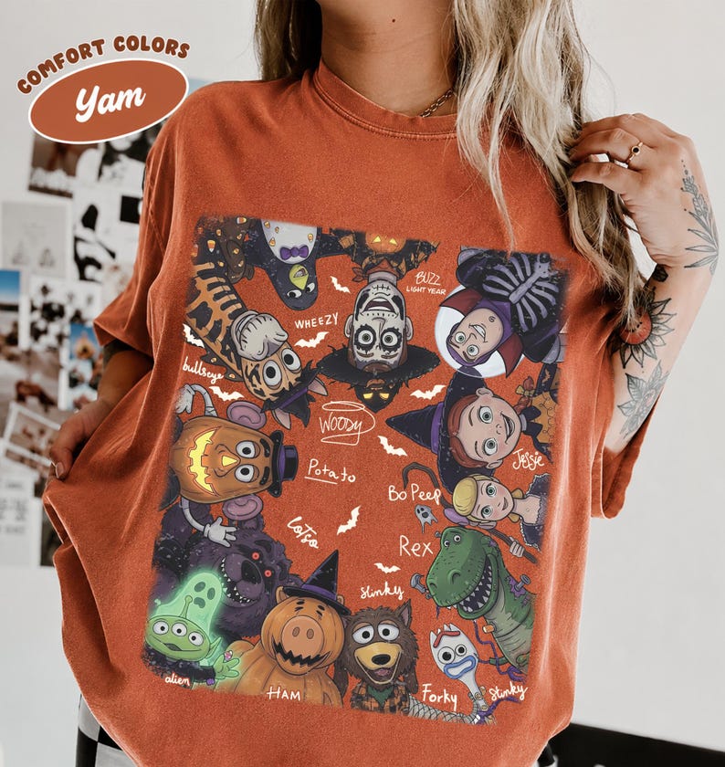 May include: A rust-colored t-shirt featuring a graphic print of various animated characters dressed in Halloween costumes. The design includes characters labeled as Woody, Buzz Lightyear, Jessie, Bo Peep, Rex, Slinky, Forky, Ham, and others.
