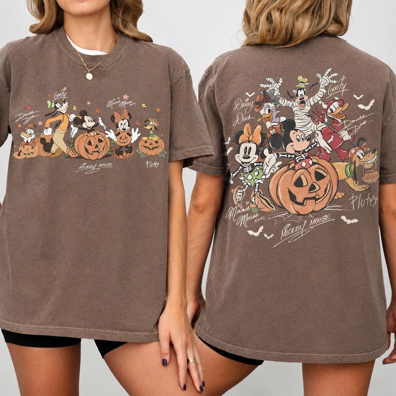 May include: Brown t-shirt featuring a Halloween-themed design with Disney characters, including Mickey Mouse, Minnie Mouse, and Goofy, with pumpkins. The front and back of the shirt display the characters and the words "Mickey Mouse".