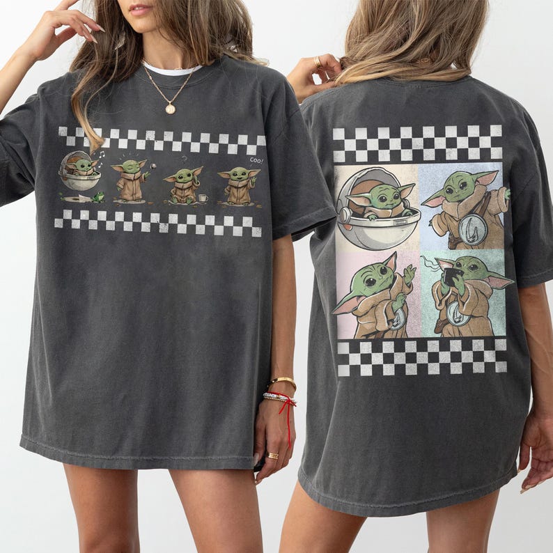 May include: Dark gray t-shirt featuring a graphic of a character in various poses, with a checkered pattern. The front of the shirt shows the character in a pod and standing. The back of the shirt shows the character in a pod, holding a device, and with a badge.