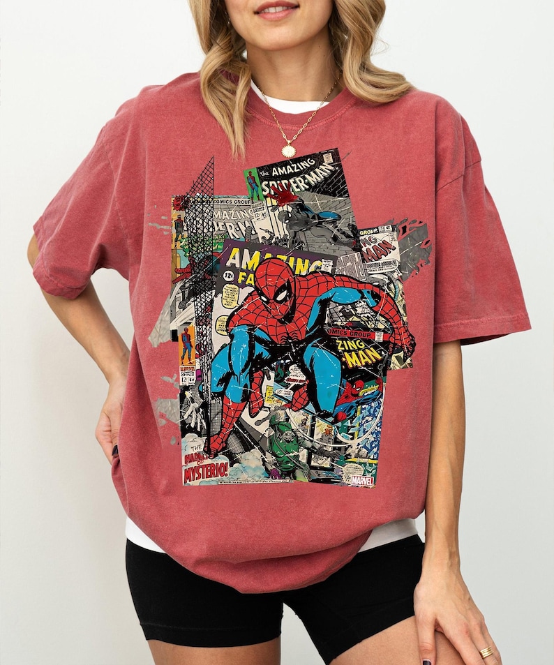 Pode incluir: Camiseta vermelha com um design de colagem de hist&oacute;rias em quadrinhos com o Homem-Aranha. O design incorpora capas de hist&oacute;rias em quadrinhos com o texto "AMAZING SPIDER-MAN" e "ZING MAN". A camiseta &eacute; de cor vermelha lisa.