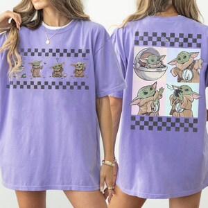 May include: A light purple t-shirt featuring a graphic of a character from a popular science fiction series. The front of the shirt displays the character in four different poses, while the back shows four more images of the character in a checkerboard pattern.