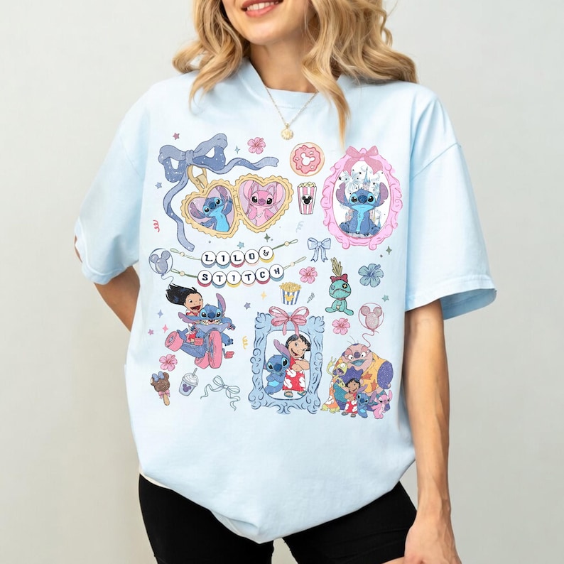 May include: Light blue t-shirt featuring colorful cartoon graphics of Stitch and Lilo from the Disney movie. The shirt includes the text "Lilo & Stitch" and various character illustrations in frames and heart-shaped sunglasses.