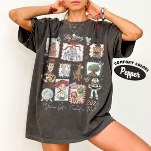 Puede incluir: Camiseta gris oscuro con un dise&ntilde;o de Toy Story. El dise&ntilde;o incluye varios personajes e im&aacute;genes de la pel&iacute;cula, como Woody y Buzz Lightyear. Tambi&eacute;n est&aacute; presente el texto "Toy Story" y "You've Got a Friend in Me". La camiseta est&aacute; etiquetada como "Comfort Colors Pepper".