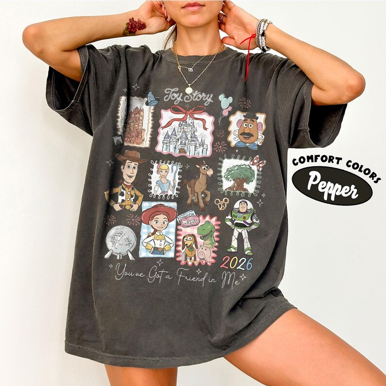 Puede incluir: Camiseta gris oscuro con un dise&ntilde;o de Toy Story. El dise&ntilde;o incluye varios personajes e im&aacute;genes de la pel&iacute;cula, como Woody y Buzz Lightyear. Tambi&eacute;n est&aacute; presente el texto "Toy Story" y "You've Got a Friend in Me". La camiseta est&aacute; etiquetada como "Comfort Colors Pepper".