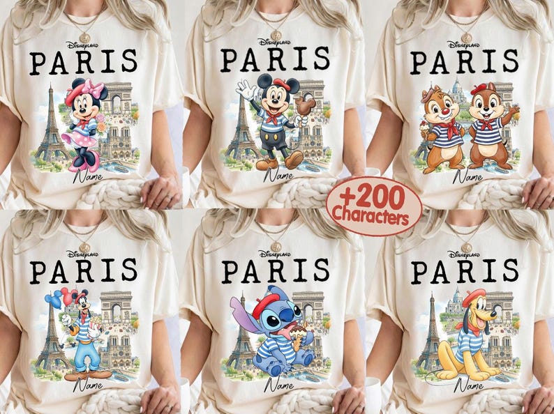 K&ouml;nnte beinhalten: Cremefarbene T-Shirts mit dem Wort "PARIS" in Schwarz, die Disney-Figuren wie Minnie Maus, Micky Maus, Chip und Chap, Goofy, Stitch und Pluto zeigen. Jedes Design enth&auml;lt den Eiffelturm und den Arc de Triomphe.