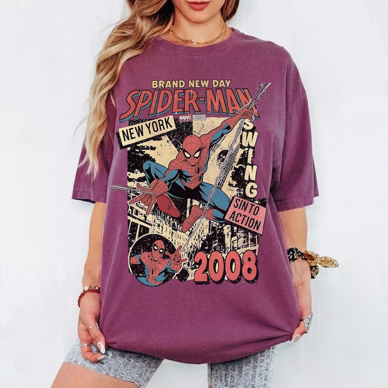 May include: A maroon t-shirt with a Spider-Man graphic. The design includes the words "BRAND NEW DAY," "SPIDER-MAN," "NEW YORK," and "SWING INTO ACTION," along with the year "2008." The superhero is shown in a dynamic pose.