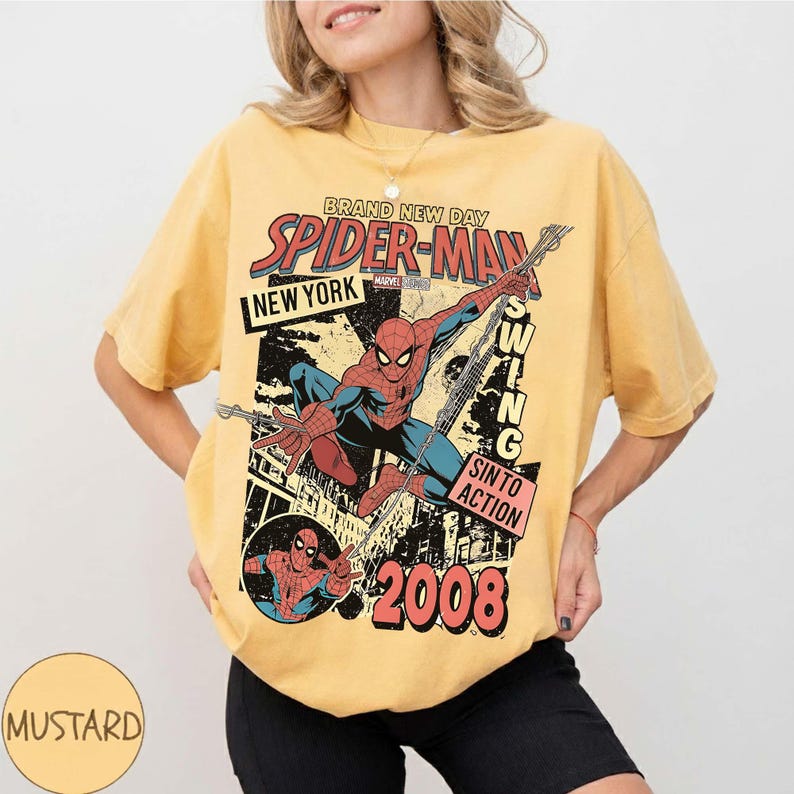 May include: Mustard-coloured t-shirt with a vintage Spider-Man graphic. The design includes the words "Brand New Day," "New York," and "Swing Into Action," with the year "2008." The graphic depicts Spider-Man in action.