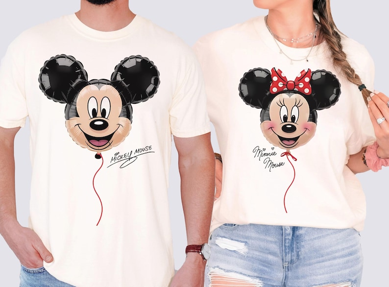 K&ouml;nnte beinhalten: Cremefarbene T-Shirts mit Mickey- und Minnie-Mouse-Ballon-Designs. Mickeys Ballon hat einen schwarzen Kopf und Ohren, ein beiges Gesicht und den Text "Mickey Mouse". Minnies Ballon hat eine rote Schleife und den Text "Minnie Mouse".
