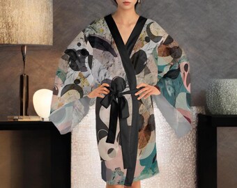 May include: A black and white abstract print silk robe with a black satin sash. The robe has a long, flowing silhouette and a relaxed fit.