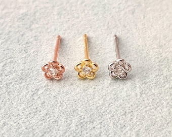 Puede incluir: Tres pendientes en forma de flor con un solo diamante en el centro. Los pendientes son de oro, oro rosa y plata.