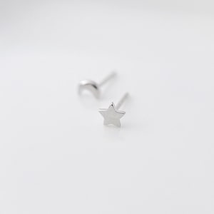 May include: A pair of silver earrings featuring a crescent moon and a star design.