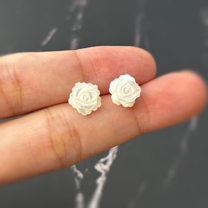 May include: A pair of white mother of pearl rose flower stud earrings.