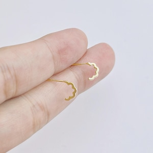 Peut inclure: Une paire de boucles d'oreilles dorées délicates. Chaque boucle d'oreille présente un motif en forme de nuage. Les boucles d'oreilles sont présentées sur un fond clair. Les boucles d'oreilles sont petites et légères.