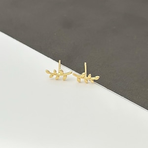 May include: A pair of gold leaf stud earrings. The earrings are small and delicate, with a simple design.