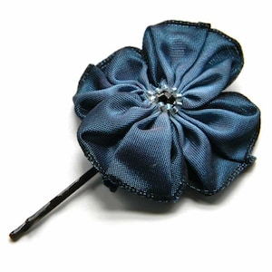 May include: A dark blue fabric flower with a silver rhinestone center, attached to a black bobby pin.