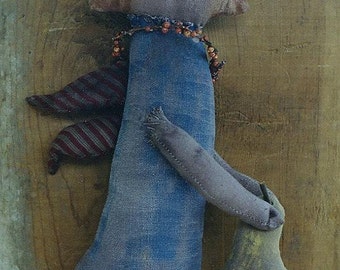 May include: A handmade rag doll with a blue dress, red and white striped wings, and a yellow fabric bag. The doll has a brown face with painted eyes and a mouth.