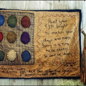 May include: A handmade quilted wall hanging with a patchwork design featuring felt circles in various colors, including red, blue, green, and yellow. The text reads "My Favorite colors of Easter eggs, Red, Blue, yellow and green. I Almost missed Purple." and "Paint your eggs bright to match your days and nights. Spring is a time to be cheery. So don't be dreary."