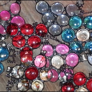 May include: Three glass and metal suncatchers with different colored glass beads. The first suncatcher has red glass beads, the second has pink glass beads, and the third has blue and clear glass beads.