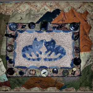 May include: A patchwork fabric art piece with a central image of two blue cats. The piece is decorated with various buttons, beads, and other embellishments.
