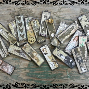 May include: A collection of 20 vintage-style rectangular pendants with various images and designs. The pendants are made of metal and have a distressed, antique look. The images include people, flowers, and other decorative elements.