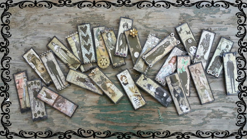 May include: A collection of 20 vintage-style rectangular pendants with various images and designs. The pendants are made of metal and have a distressed, antique look. The images include people, flowers, and other decorative elements.