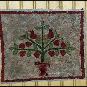 Puede incluir: Una alfombra hecha a mano con un borde rojo presenta un árbol estilizado con bayas rojas y dos pájaros posados en una rama. El árbol está en una maceta roja con un tallo verde.