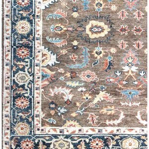 Corner of a muted wool area rug displaying the fringe and high-quality weave of the traditional border.