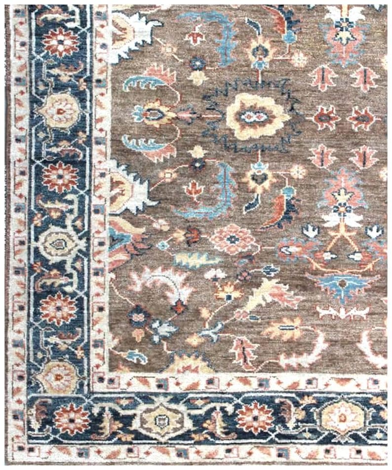 Corner of a muted wool area rug displaying the fringe and high-quality weave of the traditional border.