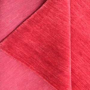 May include: Close-up of a folded red fabric with a textured surface. The fabric has a deep, rich color and appears to be made of a soft material. The folds create shadows and highlights, adding depth to the image.