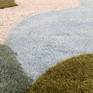 Close-up of the 3D tufted wool texture showing different pile heights in moss green and olive tones.