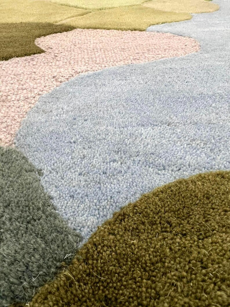 Close-up of the 3D tufted wool texture showing different pile heights in moss green and olive tones.