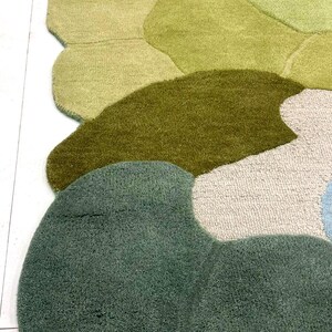 May include: A colorful, abstract area rug with a unique, organic design. The rug features various shades of green, from light to dark, with accents of blue and beige. The soft, textured surface adds visual interest and comfort to any room.