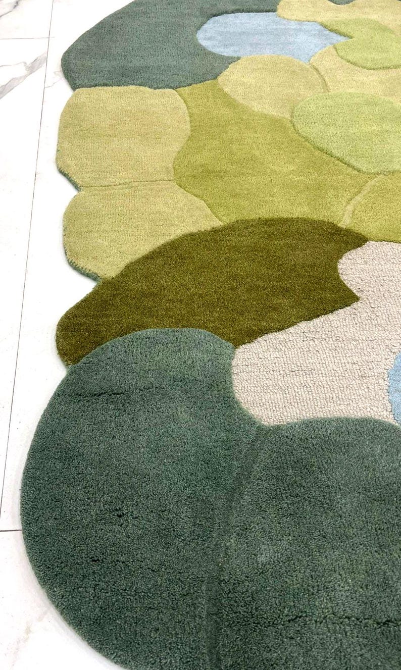 May include: A colorful, abstract area rug with a unique, organic design. The rug features various shades of green, from light to dark, with accents of blue and beige. The soft, textured surface adds visual interest and comfort to any room.