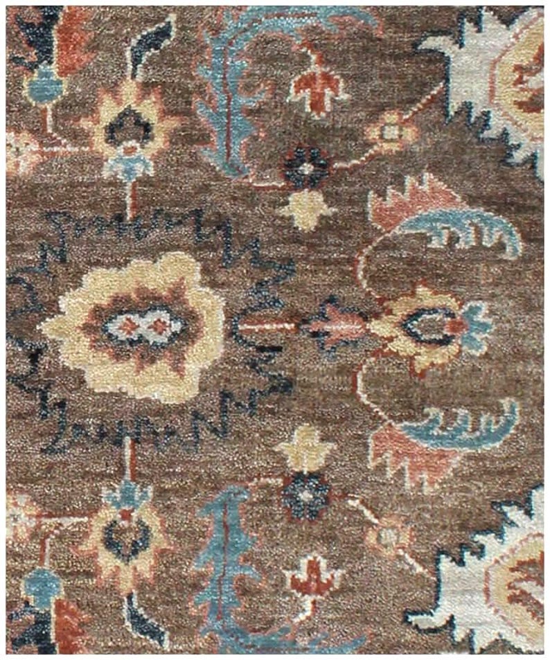Macro view of hand-knotted wool fibers showing the intricate brown and blue floral Oushak pattern details.