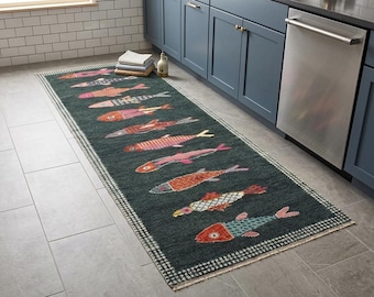 May include: A rectangular runner rug featuring a dark charcoal background with a repeating pattern of stylised fish in various colours including orange, pink, blue, and white. The rug has a chequered border and short fringe on the ends.