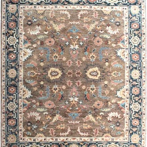 A brown rug with a floral pattern and a blue border. The rug has a traditional design with intricate details.