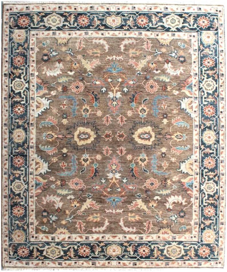 A brown rug with a floral pattern and a blue border. The rug has a traditional design with intricate details.
