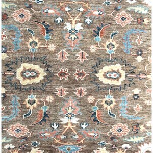 close up of A brown rug with a floral pattern in shades of blue, pink, and cream. The rug has a traditional Persian design with intricate details.