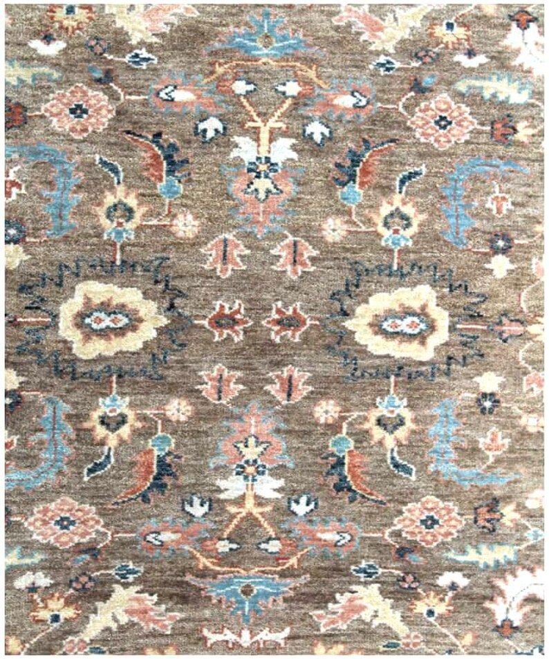 close up of A brown rug with a floral pattern in shades of blue, pink, and cream. The rug has a traditional Persian design with intricate details.